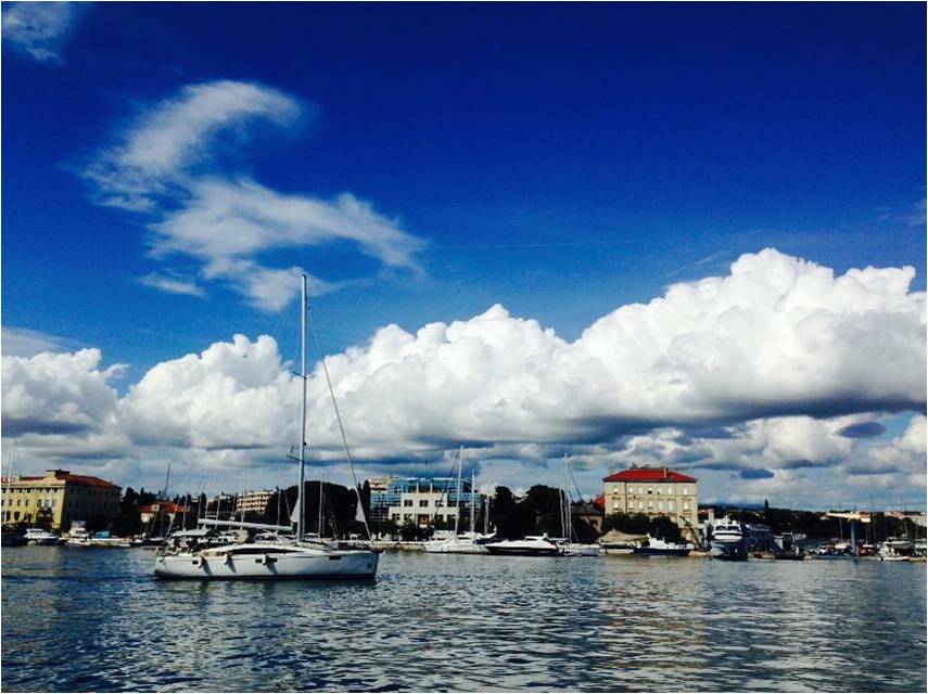 Sailboats in a harbor under dramatic clouds